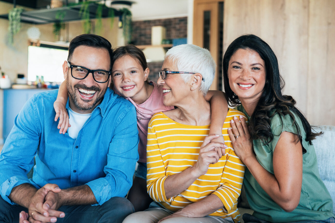 Family of four smiling together in a cozy home setting, highlighting joy and connection, relevant to discussions about dental health and family care at Sandy Springs Dentistry.